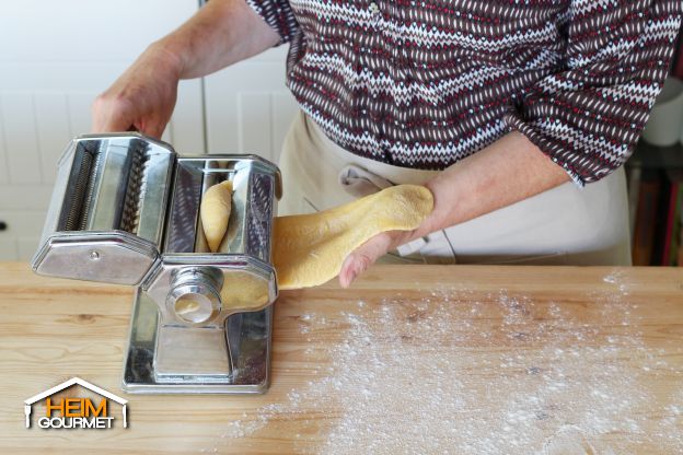 Den Teig durch die Nudelmaschine geben
